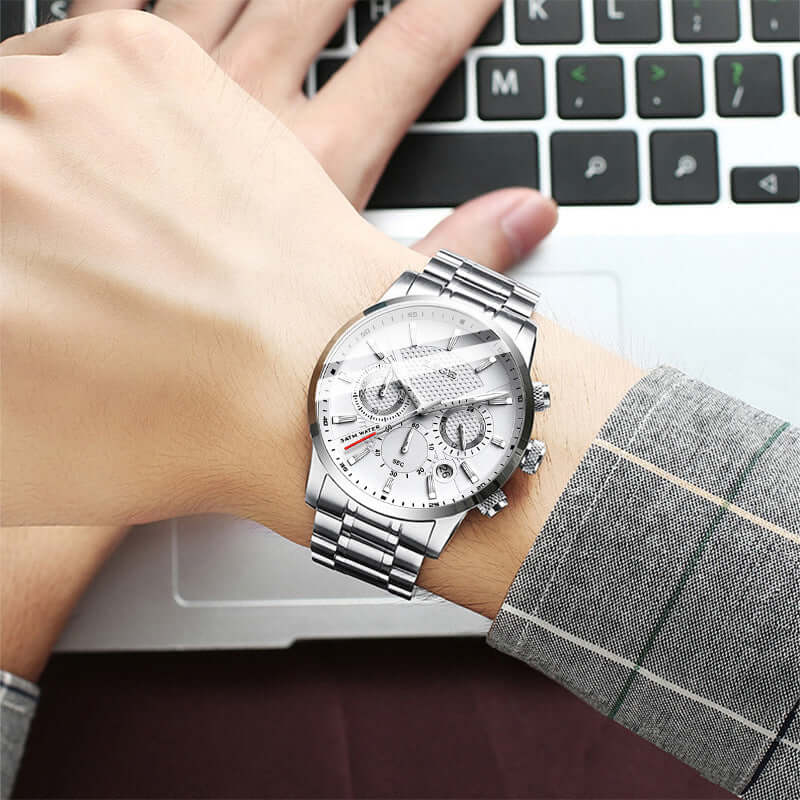 Stylish men's sport quartz watch with silver metal band, worn on wrist, beside a laptop keyboard.