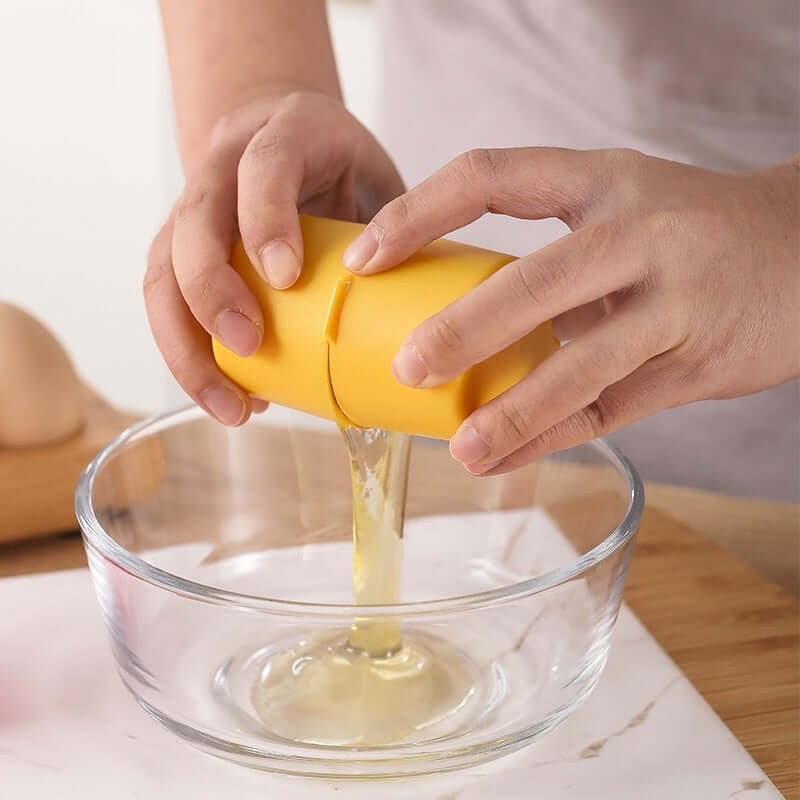 Person using a yellow egg shell opener to crack an egg into a glass bowl, demonstrating mess-free operation.